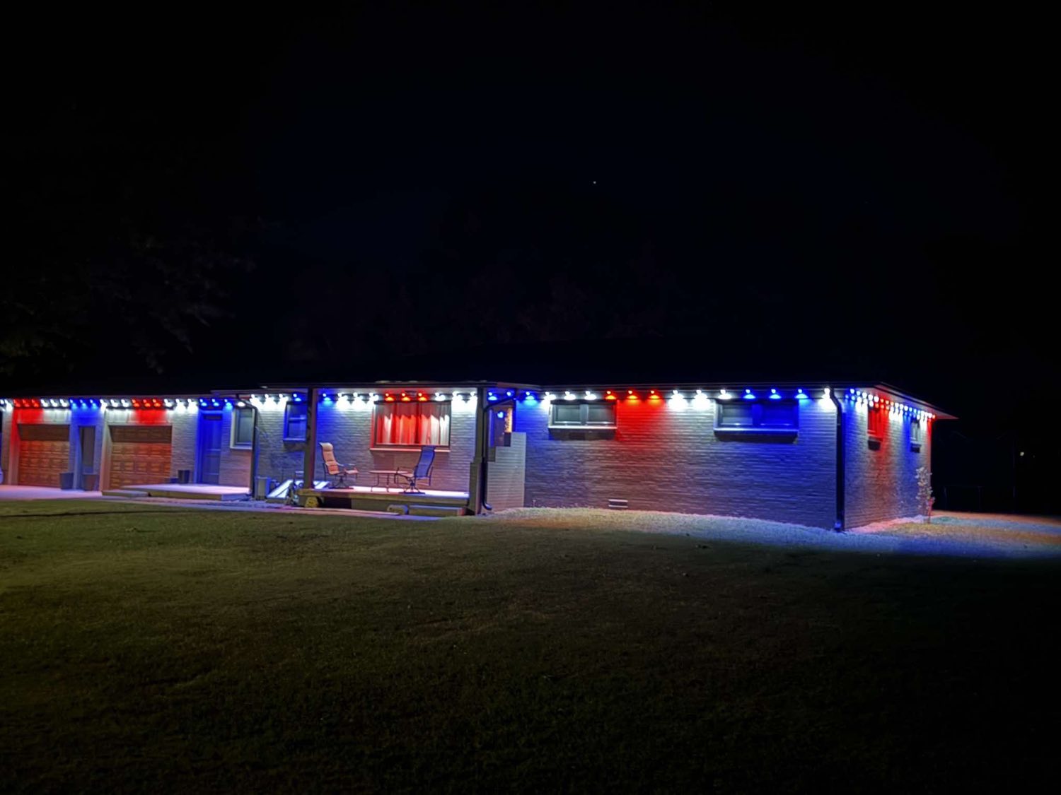 Brick ranch home lit in red, white and blue around the full roofline