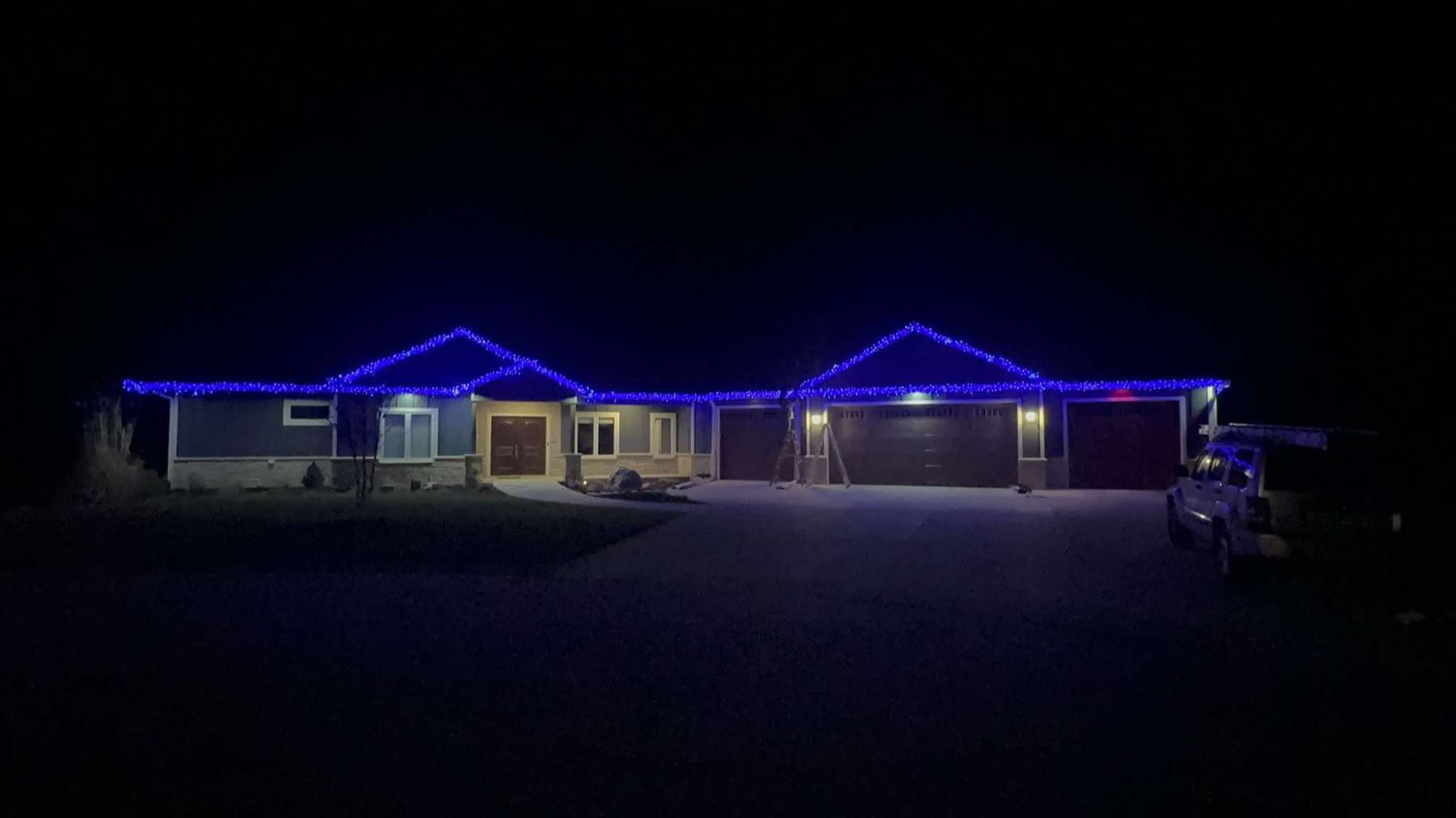 Ranch home outlined in blue Christmas lights