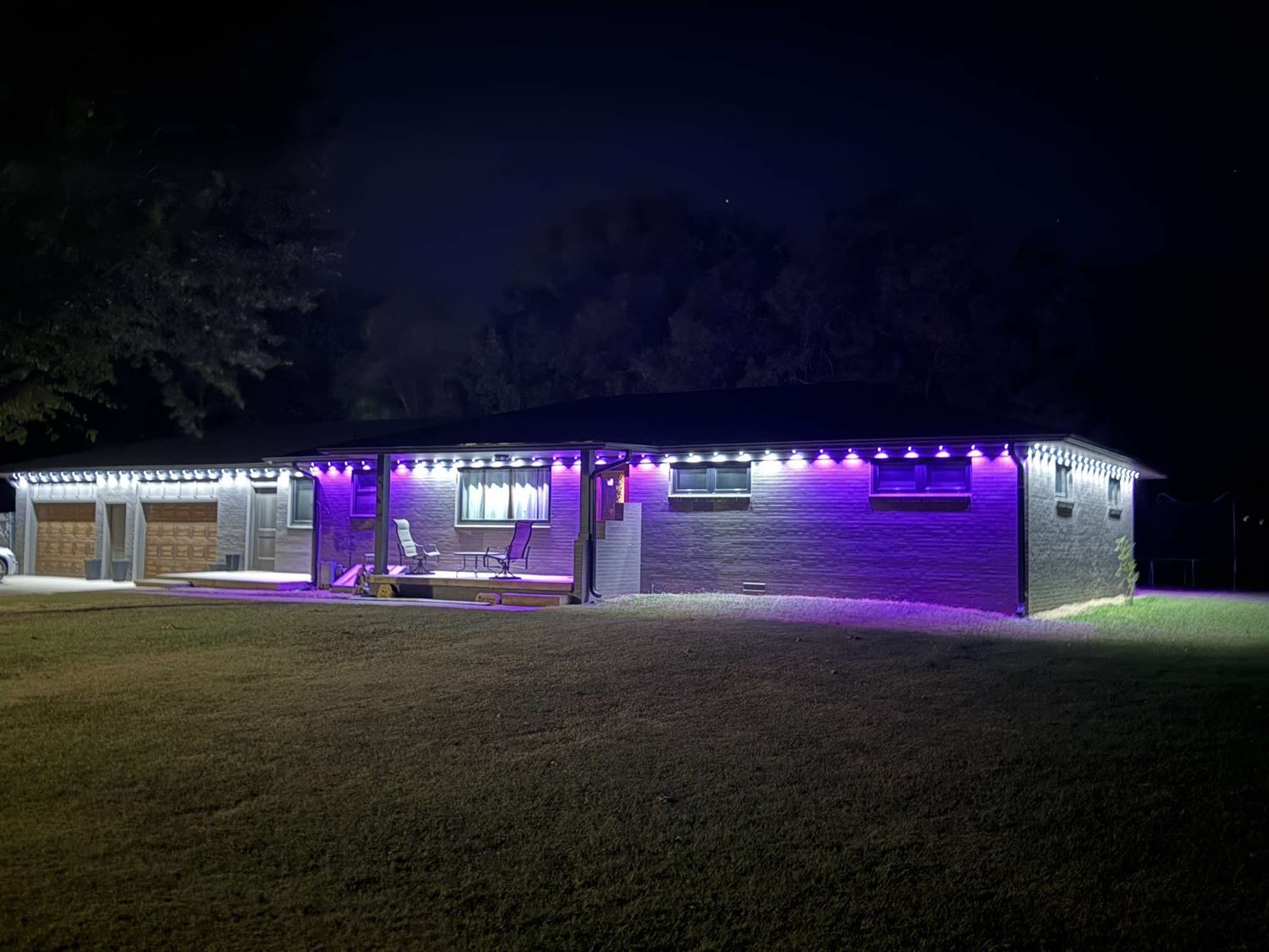 Brick ranch home lit in purple and white