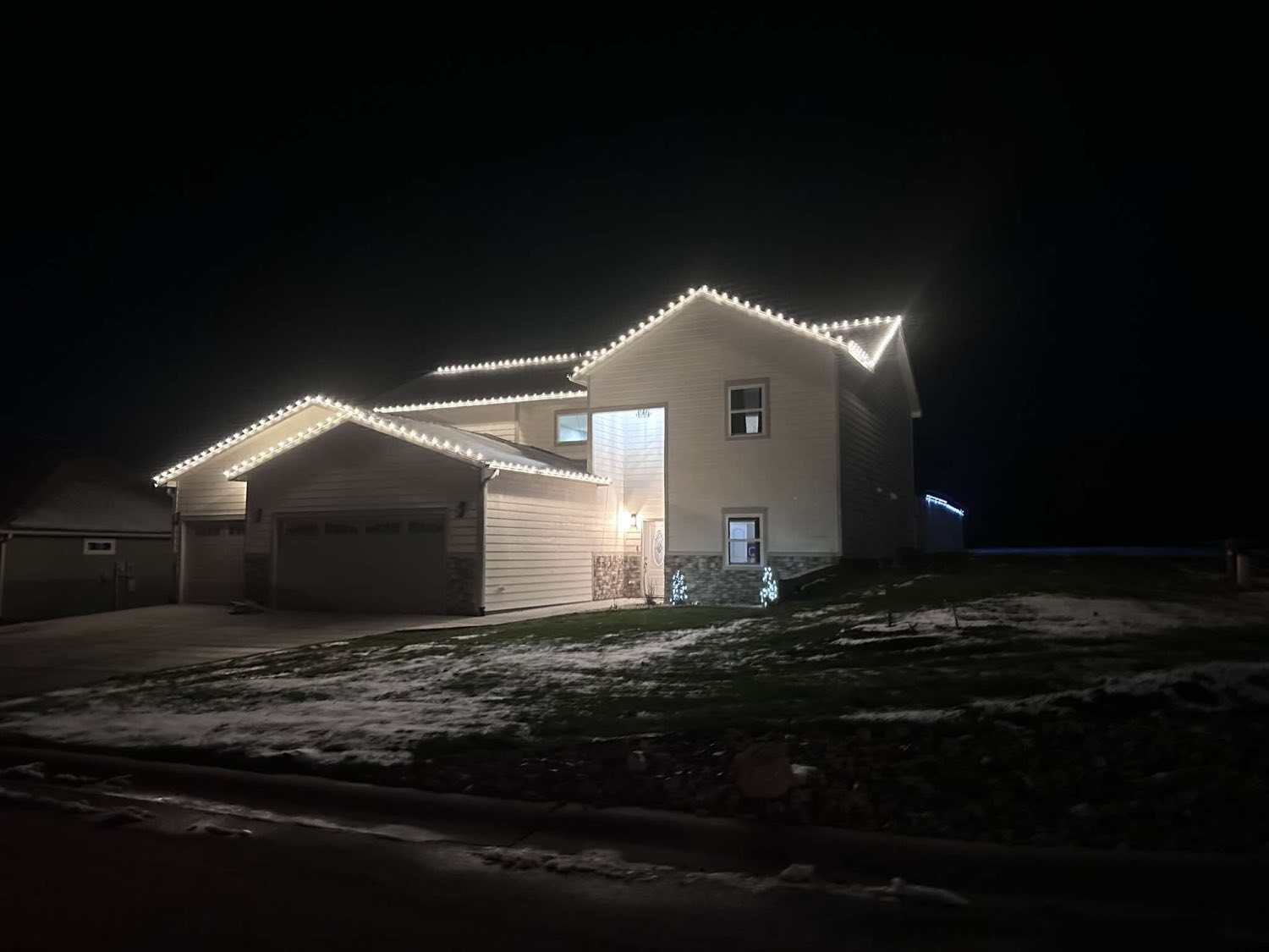 Two story home with white C9 Christmas lights on the roofline