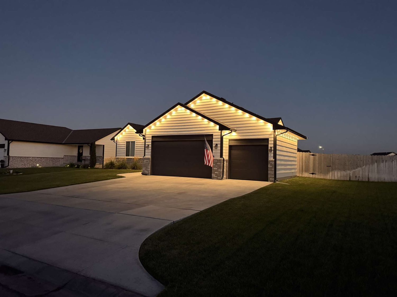 Warm white permanent lighting along the eaves and gables at dusk